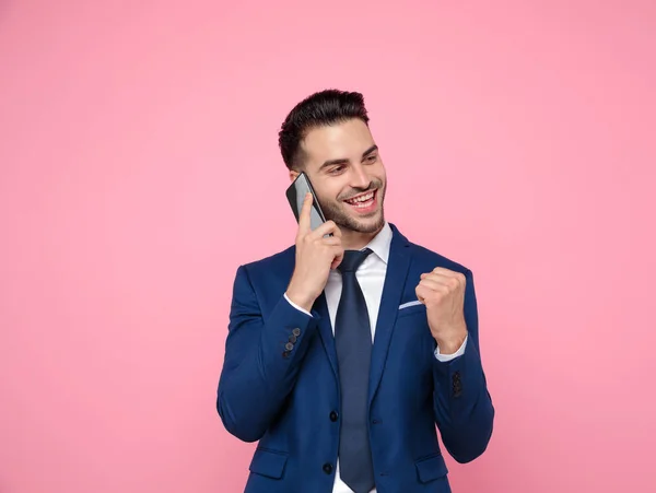 Knappe jonge man praten op de telefoon op roze achtergrond — Stockfoto