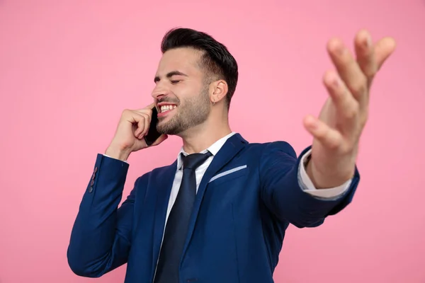Snygg ung man pratar i telefon på rosa bakgrund — Stockfoto
