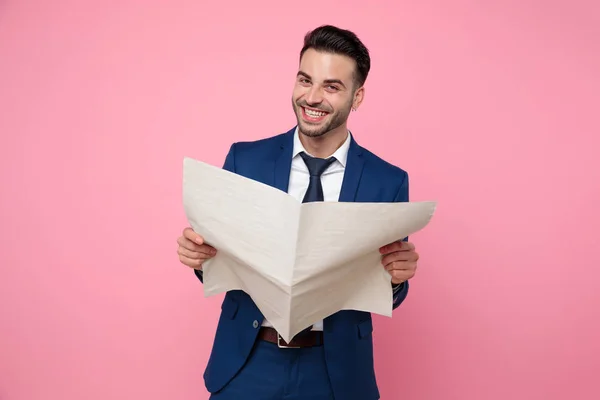 Joven guapo leyendo periódico sobre fondo rosa — Foto de Stock