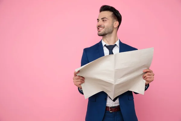 Attraente giovane uomo che tiene giornale su sfondo rosa — Foto Stock