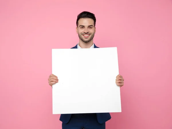 Atraktivní mladý muž držící prázdnou desku na růžovém pozadí — Stock fotografie