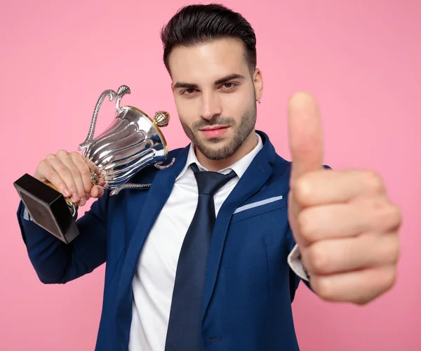 attractive young man holding victory cup and making thumbs up si