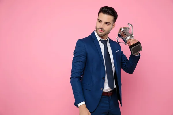 handsome young man holding victory cup on pink background