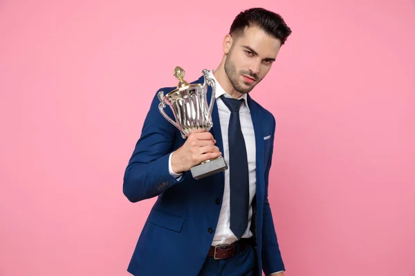 smart casual man holding victory cup on pink background
