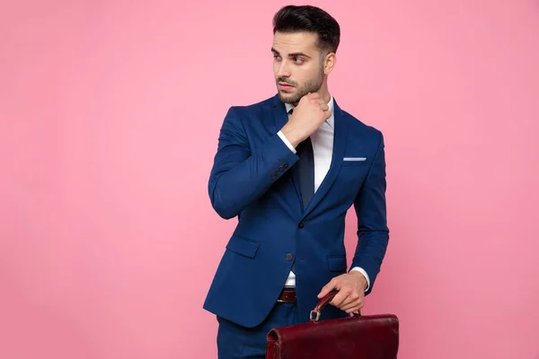 Knappe jonge man Holding koffer op roze achtergrond — Stockfoto