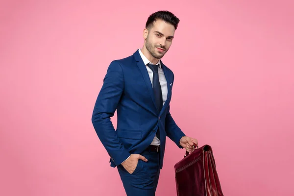 Attrayant jeune homme tenant valise sur fond rose — Photo