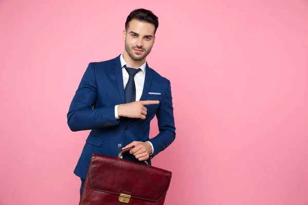 attractive young man wearing navy blue suit and suitcase