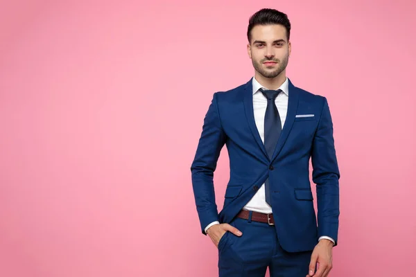 Привлекательный молодой человек в синем костюме на розовом фоне — стоковое фото