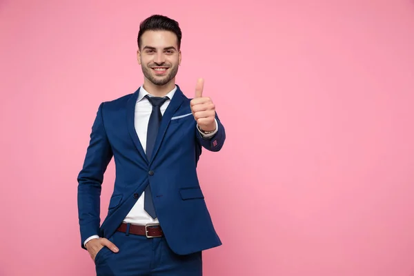 Aantrekkelijke jonge man maken duimen omhoog teken op roze achtergrond — Stockfoto