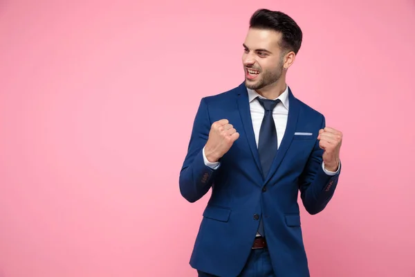Handsome young man celebrating victory on pink background — Stock Photo, Image