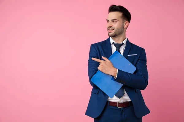 Attractive young man holding clipboard and pointing finger — Stock Photo, Image