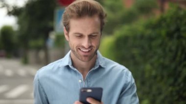 genç rahat adam yürür ve cep telefonundan haber okur