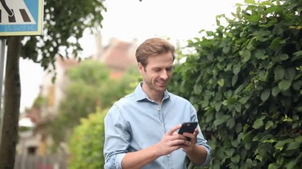 Feliz Homem Casual Mensagens Texto Seu Telefone Faz Uma Saudação — Vídeo de Stock