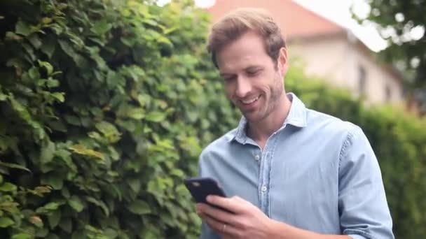 Glimlachend Casual Man Loopt Sms Zijn Mobiele Telefoon Terwijl Rond — Stockvideo