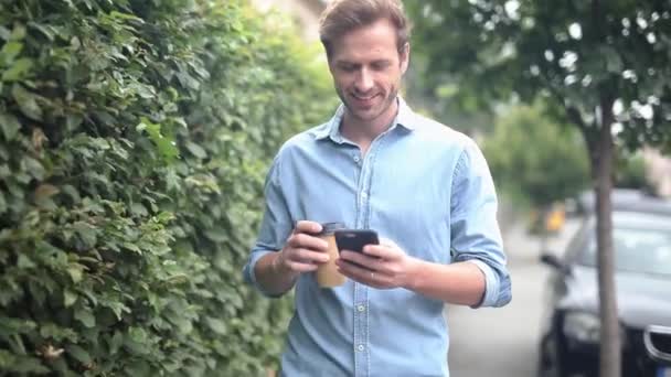 Jonge Casual Man Loopt Leest Mail Telefoon Drinkt Koffie Lacht — Stockvideo