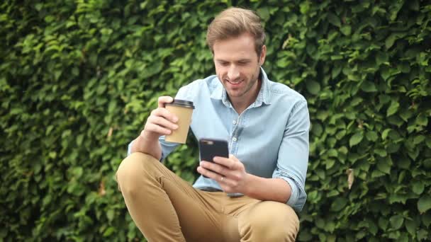 Joven Feliz Tomar Sorbo Café Mientras Usa Teléfono Inteligente Calle — Vídeos de Stock