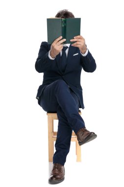 bir kitap ile kaplı yüzü ile oturan işadamı