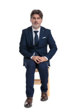 işadamı oturan ve ciddi el ele tutuşan kamera bakıyor