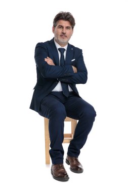 kamera confiden bakarak çapraz kolları ile oturan işadamı