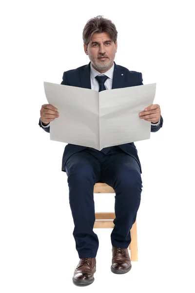 Formell affärsman sitter med tidningen på händer tittar på ca — Stockfoto