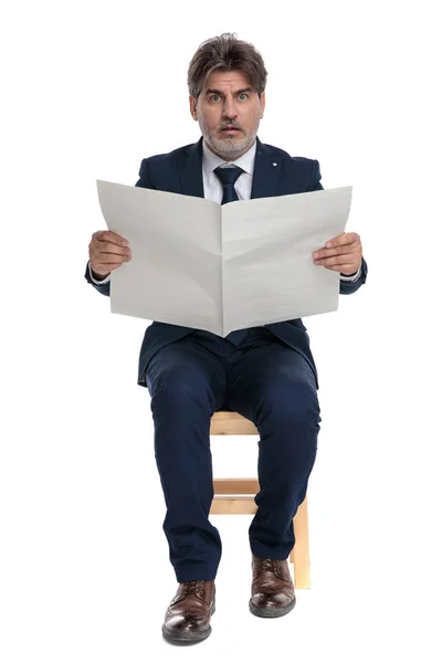 Formele zakenman zittend met krant op handen geschokt — Stockfoto