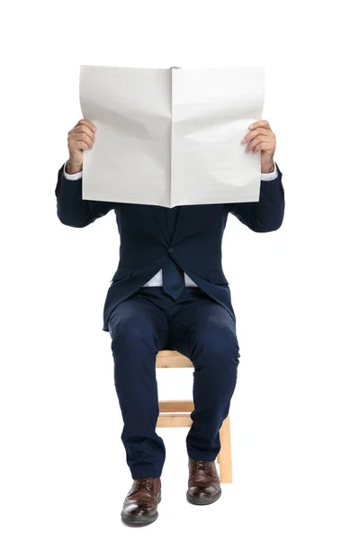 Geschäftsmann sitzt mit schüchternem Gesicht vor der Zeitung — Stockfoto