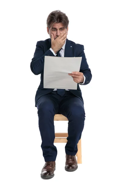 Formell affärsman sittande och läsa tidningen skräckslagen — Stockfoto