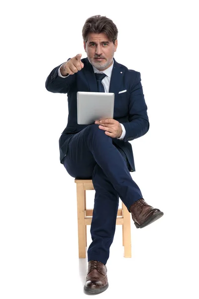 Hombre de negocios sentado con libro por un lado apuntando hacia adelante confi —  Fotos de Stock