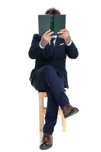 Zakenman zittend met gezicht bedekt door een boek — Stockfoto