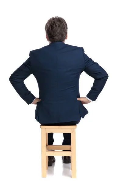 Empresário sentado com as mãos na cintura intrigado — Fotografia de Stock