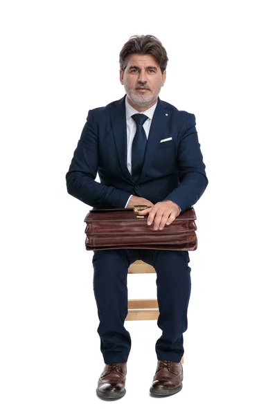 Бизнесмен сидит и держит свой портфель на коленях — стоковое фото