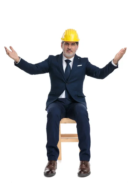 Homem de negócios com capacete de segurança sentado e cumprimentando com ar aberto — Fotografia de Stock
