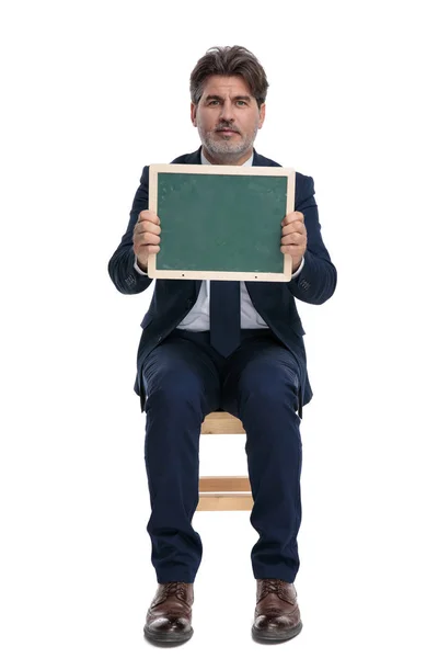 Uomo d'affari seduto e tenendo un cartellone verde felice — Foto Stock