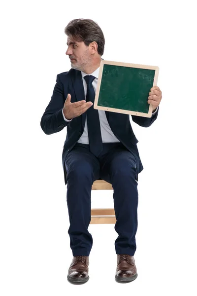 Επιχειρηματίας που κάθεται και παρουσιάζει την πράσινη αφίσα του — Φωτογραφία Αρχείου