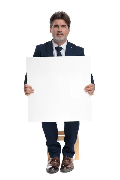 Geschäftsmann sitzt und hält eine Werbetafel glücklich in den Händen — Stockfoto