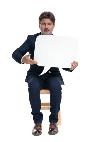 Uomo d'affari seduto e presentando una bolla discorso — Foto Stock