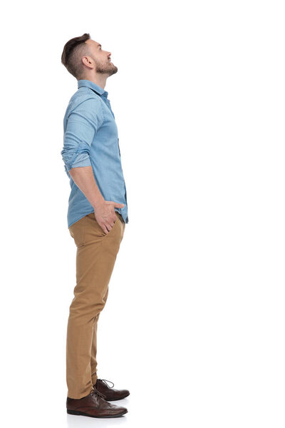 casual man standing in line and looking up curious