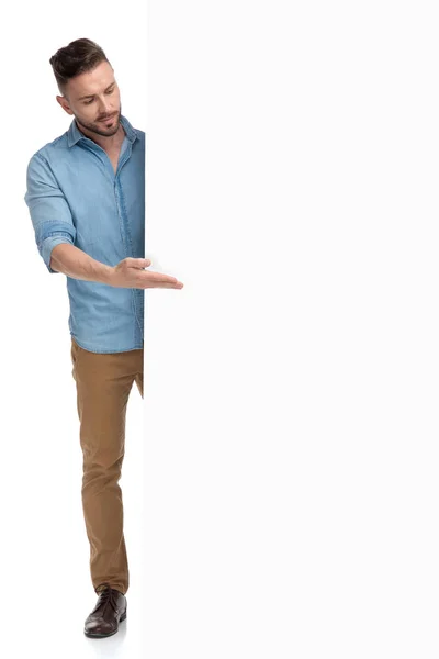 Lässiger Mann, der hinter Plakatwand steht und präsentiert — Stockfoto