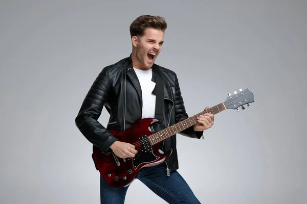 Homem casual tocando sua guitarra emocionado — Fotografia de Stock