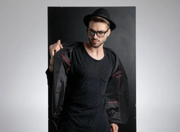 Arrogant smart casual man holding black coat in studio — Stock Photo, Image