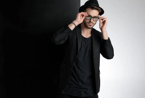Sensual young man fixing glasses in studio — Stock Photo, Image
