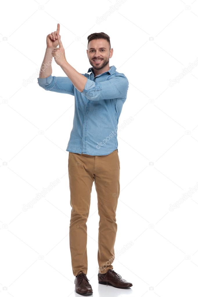 casual man standing and pointing up happy