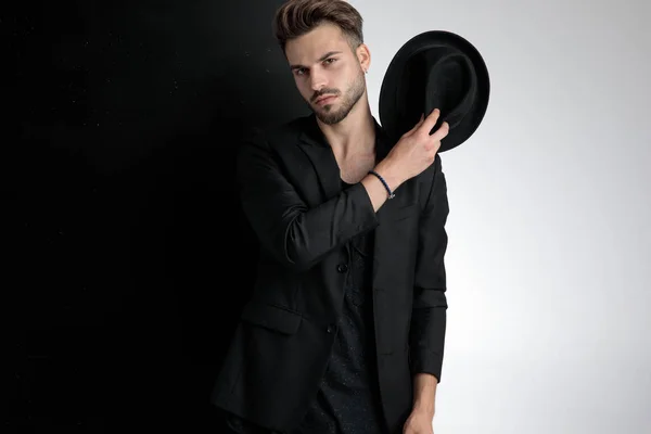 Homme décontracté intelligent arrogant tenant le chapeau sur l'épaule en studio — Photo