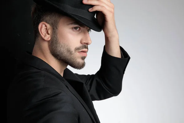 Cortés inteligente casual hombre sosteniendo negro sombrero en estudio — Foto de Stock