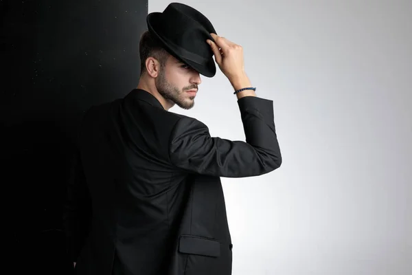 Вежливый молодой человек с черной шляпой в студии — стоковое фото