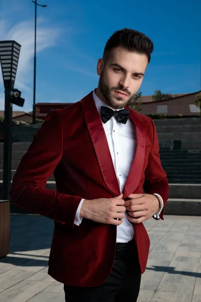 Fiducioso giovane uomo elegante fissaggio cappotto all'aperto — Foto Stock