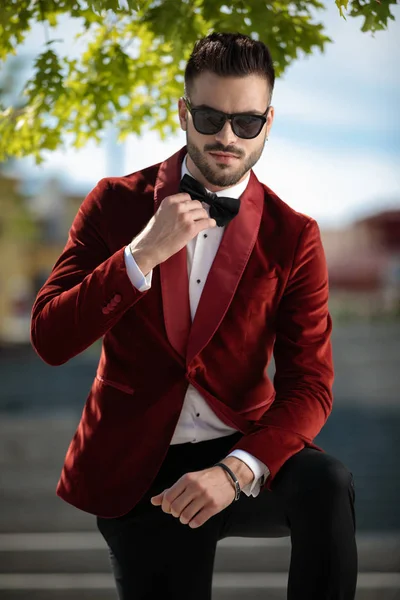 Giovane uomo sicuro di sé che indossa uno smoking di velluto rosso e organizza bowt — Foto Stock