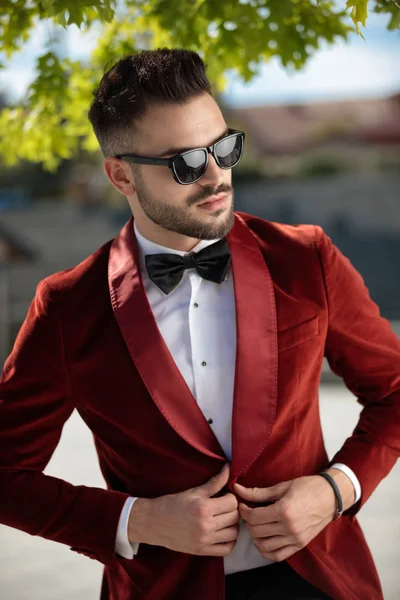 Confident young elegant man arranging red velvet tuxedo — Stock Photo, Image