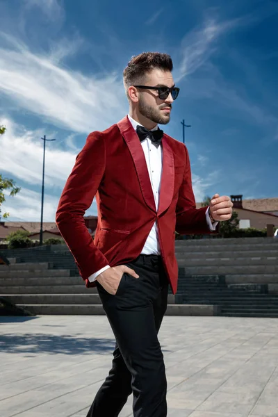 arrogant young man wearing red velvet coat and walking