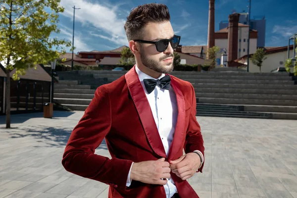 Serieuze jonge elegante man arrangeren rode fluwelen jas — Stockfoto